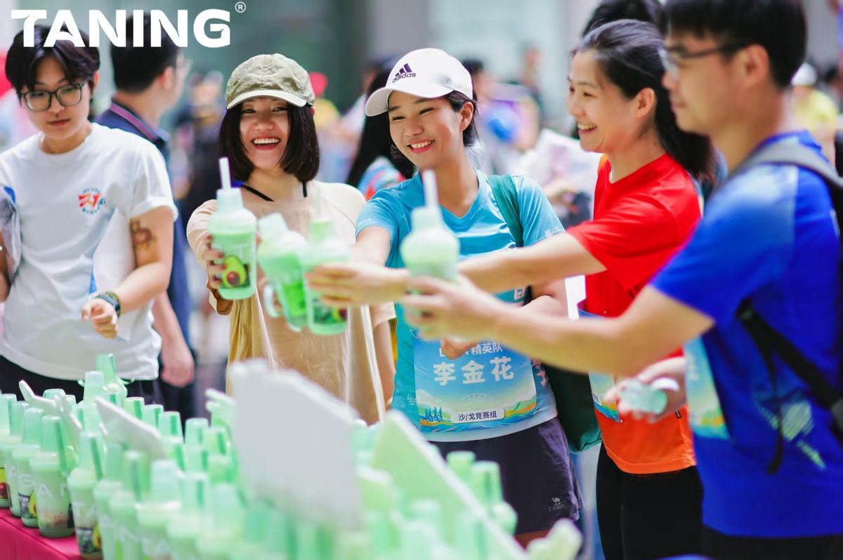 TANING果蔬茶联袂暨南大学迎新悦跑,超A牛油果的轻氧时刻! 秋风送爽,青春飞扬 | TANING果蔬茶携手暨南大学,共创轻氧迎新跑 金秋十月,活力迸发。10月12日,「迎接新力,悦动暨南」暨南大学迎新跑步活动在灿烂阳光下圆满落幕。TANING果蔬茶以一杯杯清新健康的饮品,为暨南学子的青春画卷添上了一抹亮丽的“轻氧绿”。 活动现场,TANING果蔬茶特别设置的活力补给站成为焦点。100杯明星产品「超A牛油果」系列,为挥洒汗水的奔跑者们提供了即时、轻盈的能量补充。 该系列严选源自加州、果仁