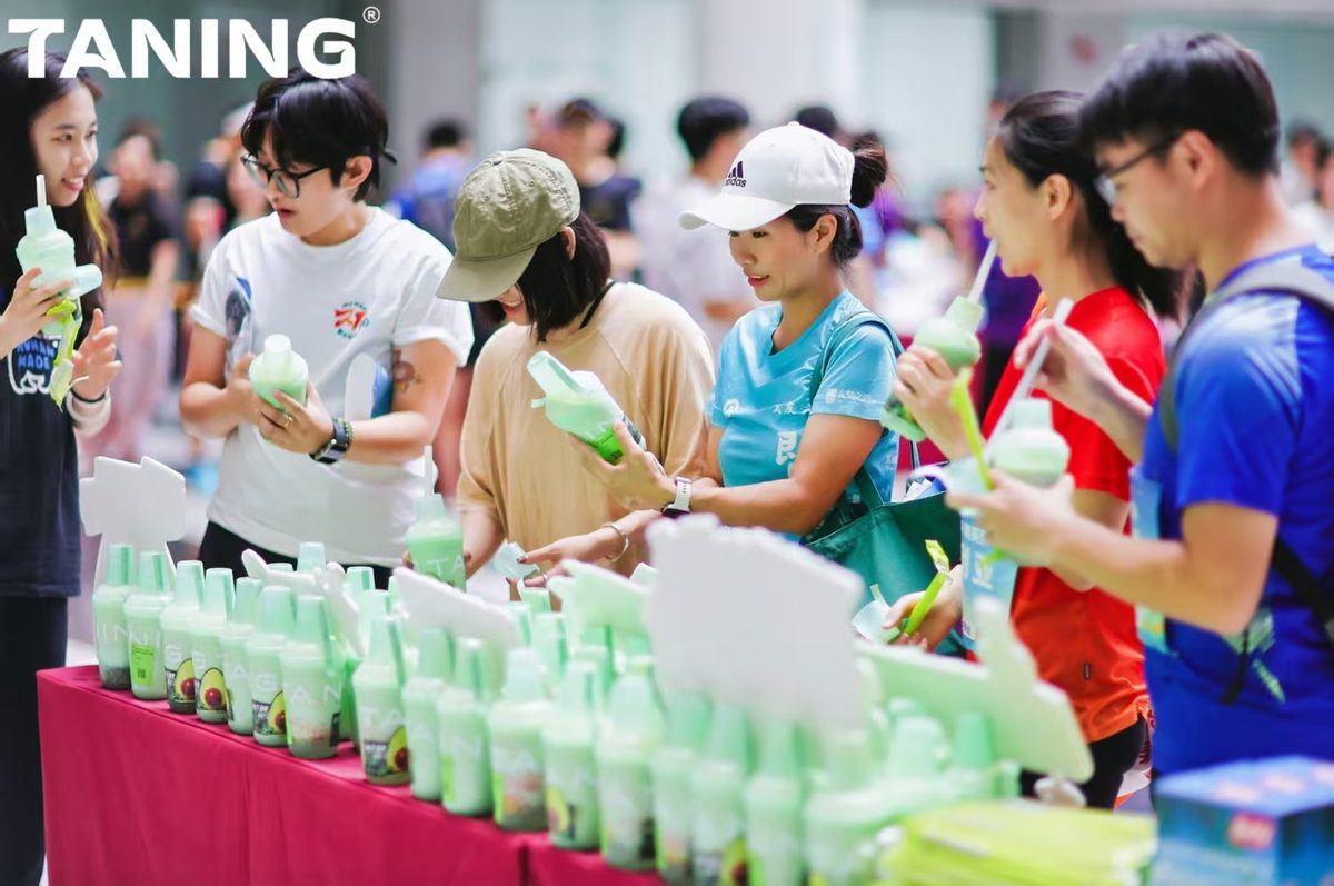 TANING果蔬茶联袂暨南大学迎新悦跑,超A牛油果的轻氧时刻! 秋风送爽,青春飞扬 | TANING果蔬茶携手暨南大学,共创轻氧迎新跑 金秋十月,活力迸发。10月12日,「迎接新力,悦动暨南」暨南大学迎新跑步活动在灿烂阳光下圆满落幕。TANING果蔬茶以一杯杯清新健康的饮品,为暨南学子的青春画卷添上了一抹亮丽的“轻氧绿”。 活动现场,TANING果蔬茶特别设置的活力补给站成为焦点。100杯明星产品「超A牛油果」系列,为挥洒汗水的奔跑者们提供了即时、轻盈的能量补充。 该系列严选源自加州、果仁